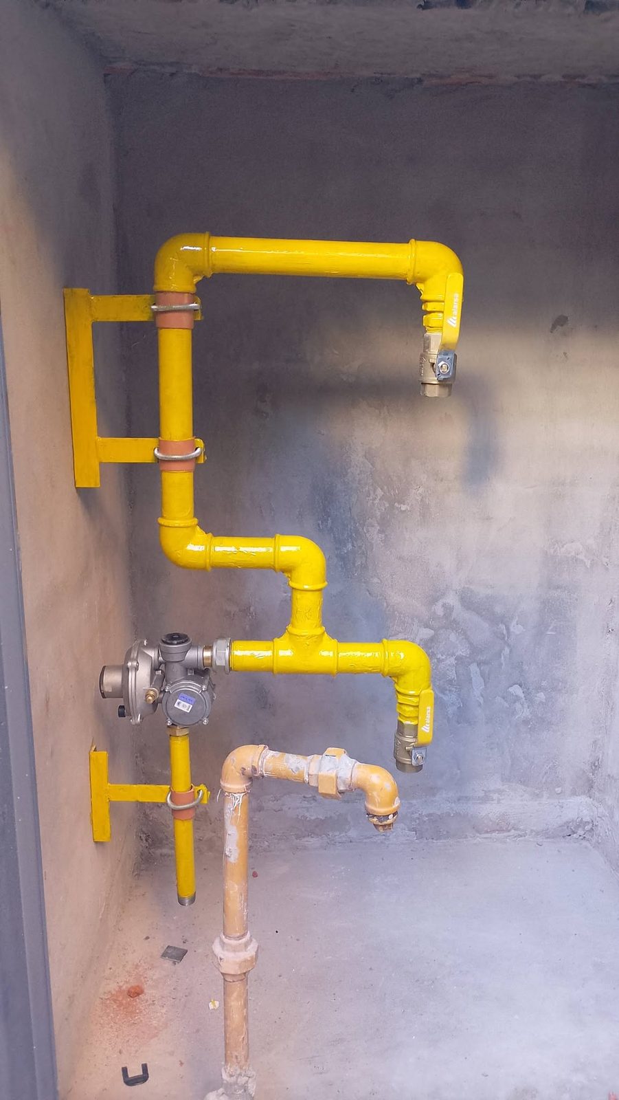 Instalación de gas: regulador y cañería pintada de amarillo
